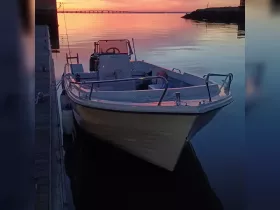 A serene view of a boat docked at sunset, reflecting the vibrant colors of the sky on calm waters — perfect for capturing the tranquility of evening boating.