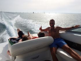 A group enjoys a sunny day on a boat, relaxing and soaking up the sun — perfect for a fun day out on the water.