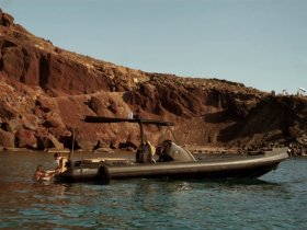 A couple enjoys a refreshing swim near a sleek boat, set against a stunning rocky coastline — perfect for adventurous outings and scenic explorations.