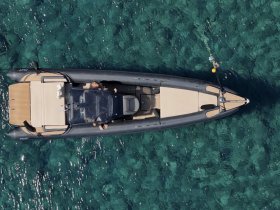 Aerial view of a sleek speedboat anchored in crystal-clear waters, showcasing its elegant design and perfect for thrilling water adventures.