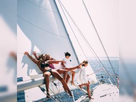 A joyful group of friends and children enjoy sailing on a yacht, capturing the essence of fun and adventure on the open water.
