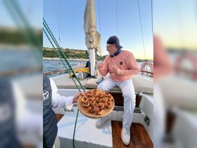 A guest enjoys delicious appetizers aboard a sailboat, showcasing the perfect blend of gourmet dining and sailing experience.