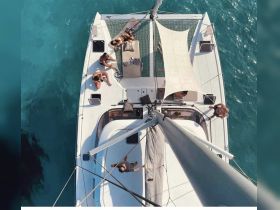A lively group enjoys sunbathing and relaxing on the deck of a catamaran, surrounded by stunning turquoise waters — perfect for a day of fun and leisure on the water.