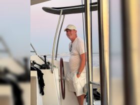 A man stands at the helm of a boat, enjoying the serene views while navigating the waters. The interior cabin showcases a modern design, perfect for comfortable cruising.