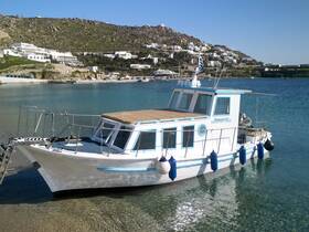 A picturesque view of the 'Katerina' boat docked in calm waters, surrounded by scenic hills and whitewashed buildings, perfect for exploring the beautiful coastline.