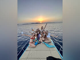 A lively group of friends celebrates at sunset aboard a boat, enjoying cocktails and creating unforgettable memories on the water.