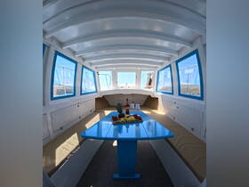 Interior view of a boat cabin featuring a dining area with a vibrant blue table, fresh fruit, and drinks, perfect for relaxing and enjoying meals on the water.
