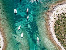 A stunning aerial view of several yachts anchored in crystal-clear waters, showcasing the beauty of the coastline and vibrant marine life.