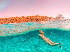 A swimmer enjoys the vibrant underwater scenery while a boat is anchored nearby, capturing the essence of a perfect day on the water.