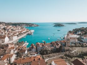 A stunning aerial view of a picturesque harbor surrounded by charming coastal architecture and lush islands, perfect for showcasing the beauty of seaside destinations.