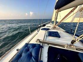 A serene view of the interior seating area on a sailboat, showcasing comfortable cushions and the tranquil sea beyond — perfect for relaxing while sailing.