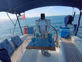 A cozy interior view of a sailboat's helm area, featuring comfortable seating and a dining setup, perfect for enjoying meals while cruising on the water.