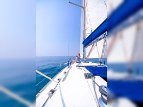 A woman enjoys a relaxing moment on the deck of a sailboat, surrounded by calm ocean waters — a perfect scene for sailing enthusiasts and leisure seekers.