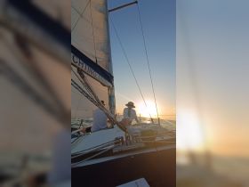 A couple enjoys a romantic sunset sail aboard a yacht, capturing the serene beauty of the ocean and the perfect end to a day on the water.