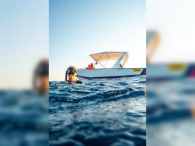 A snorkeler enjoys the ocean while a boat is visible in the background, capturing the essence of a fun-filled day on the water.
