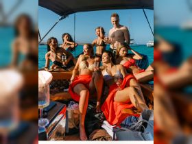 A lively group of friends enjoys a fun day on a yacht, celebrating with cocktails and soaking up the sun — perfect for summer parties and memorable outings on the water.