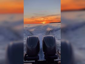 A stunning sunset view from the back of a boat, showcasing the powerful engines and the tranquil waters, perfect for evening cruises.