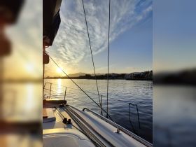 A serene view of a sailboat at sunset, showcasing the tranquil waters and beautiful sky — perfect for peaceful sailing experiences.