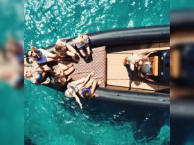A lively group of friends enjoys a fun day on a boat, soaking up the sun and celebrating in the crystal-clear waters — perfect for unforgettable summer adventures.