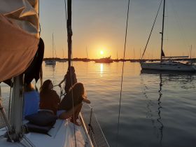 A group of friends enjoys a serene sunset while sailing, creating a perfect backdrop for relaxation and memorable moments on the water.