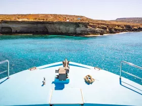 A stunning view from the bow of a boat, showcasing the vibrant turquoise waters and rocky coastline — perfect for exploring scenic destinations.