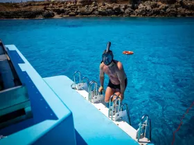 A man emerges from the vibrant blue waters after snorkeling, showcasing the excitement of underwater exploration in a stunning marine environment.