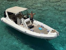 A man poses on a stylish boat in crystal-clear waters, perfect for summer adventures and exploring beautiful coastlines.