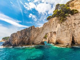 A stunning view of a rocky coastline with vibrant turquoise waters, showcasing a natural arch — perfect for exploring scenic destinations by boat.