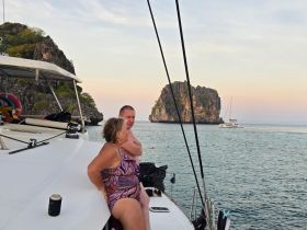 A couple enjoys a serene moment on the deck of their boat, surrounded by stunning rock formations and tranquil waters — perfect for a romantic getaway.
