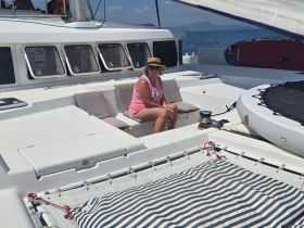 A woman relaxes in the seating area of a catamaran, enjoying the sun and sea breeze — perfect for leisurely days on the water.