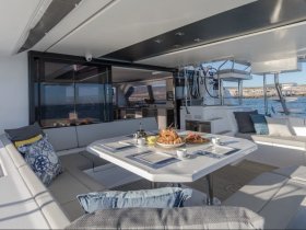 An elegant dining area inside a modern boat, featuring comfortable seating and a beautifully arranged table with food, perfect for enjoying meals while cruising.