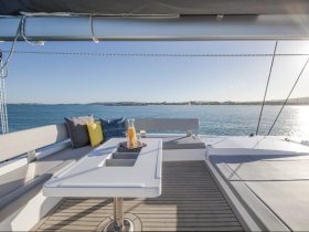 A beautifully arranged dining area on a catamaran, featuring comfortable seating and a refreshing drink, perfect for enjoying meals while cruising on the water.