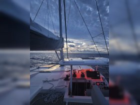 A serene view of the helm area on a catamaran, showcasing the console and ropes against a dramatic sky, perfect for evening sailing adventures.