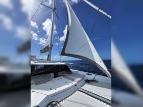 A stunning view of a catamaran's sail and deck, showcasing the sleek design and vibrant blue skies, perfect for sailing enthusiasts.