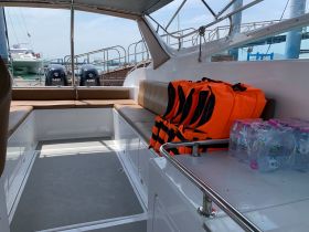 Interior view of a boat showcasing seating arrangements, safety life jackets, and bottled water — ideal for ensuring passenger comfort and safety during trips.