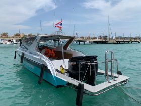 A sleek speedboat docked in clear turquoise waters, showcasing its modern design and powerful outboard engines, perfect for thrilling water adventures.