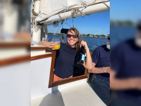 A woman enjoys a refreshing drink aboard a yacht, celebrating with friends on a sunny day — perfect for memorable outings on the water.