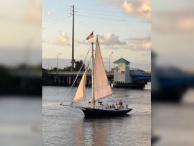 A beautiful sailboat glides through the water with a group of people onboard, showcasing a perfect day for sailing and enjoying the scenic views.