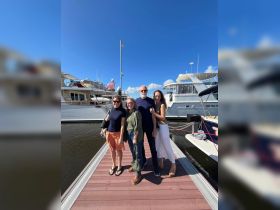 A cheerful group poses together at the marina, surrounded by beautiful yachts — perfect for family gatherings or memorable boating trips.