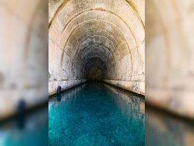 An interior view of a tunnel with clear water, showcasing an intriguing architectural structure but lacking identifiable features.