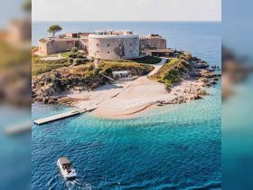 A picturesque aerial view of a historic fort on an island, with a boat cruising nearby — a perfect destination for exploration and scenic boat trips.