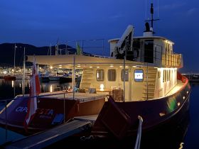 A beautifully lit boat named 'Capriesta' docked at night, showcasing its elegant design against a serene harbor backdrop.