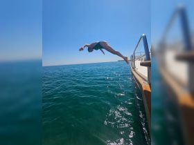 A person dives off the side of a boat into the sparkling blue waters, capturing the thrill of summer fun and on-water activities.