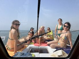 A lively group of friends enjoys a sunny day on the boat, soaking up the sun and celebrating together in stylish bikinis — perfect for a fun day on the water.