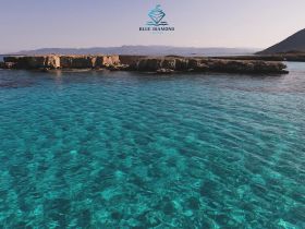 A stunning view of crystal-clear turquoise waters and a rocky coastline, perfect for showcasing the beauty of island destinations and boating adventures.