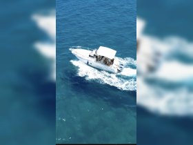A sleek boat cruises through clear blue waters, showcasing a lively day on the water with guests enjoying the ride.