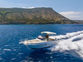 A sleek boat speeds through vibrant blue waters, showcasing a stunning coastal backdrop — perfect for adventure seekers and scenic boat tours.