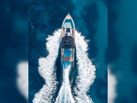 A stunning aerial view of a sleek speedboat cruising through crystal-clear waters, showcasing its elegant design and powerful wake.