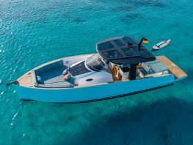 A stunning aerial view of a sleek yacht cruising through crystal-clear waters, showcasing its elegant design and spacious deck — perfect for luxury outings and island adventures.
