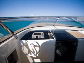 A sleek view of the helm and console area inside a modern boat, showcasing the stylish design and functionality for navigating the open waters.